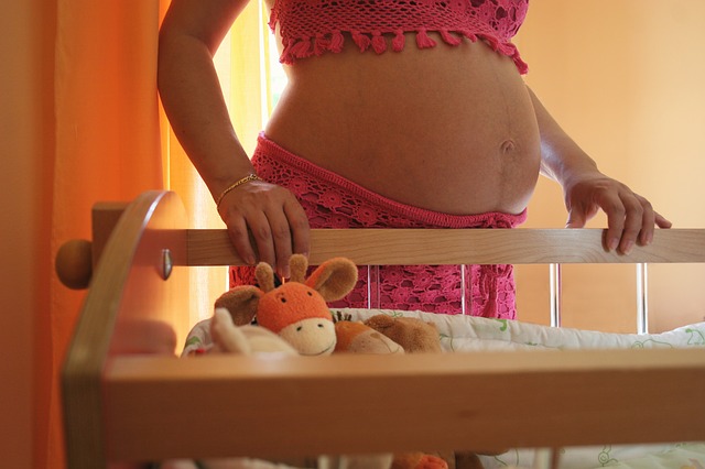 kobieta w ciąży przy dziecięcym łóżeczku