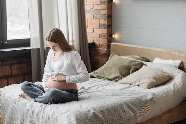 Kobieta w ciąży siedząca na łóżku