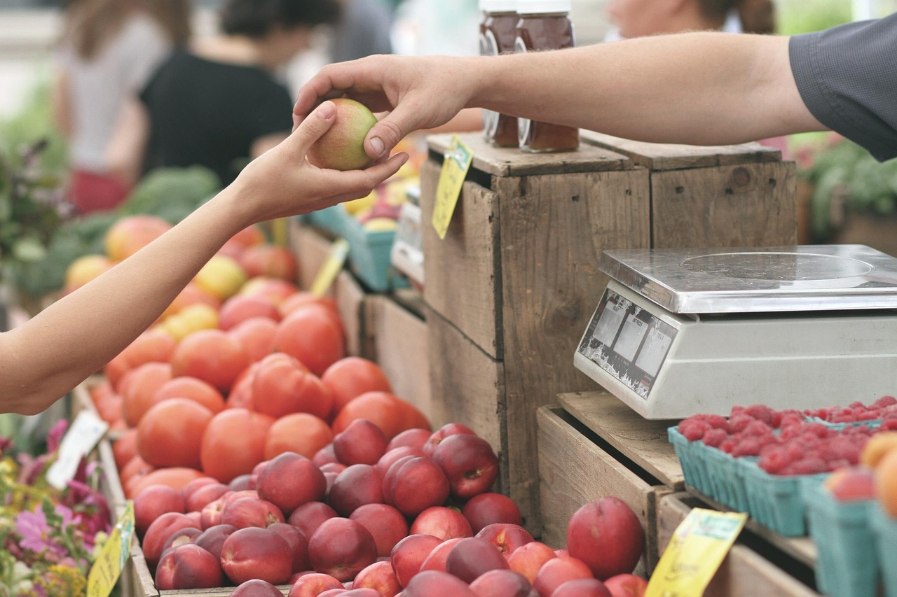 Sprzedawca podaje świeże owoce i warzywa na straganie z lokalnymi produktami